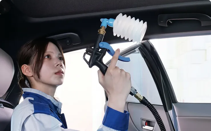 スタッフが専用液剤を車内に噴霧する様子