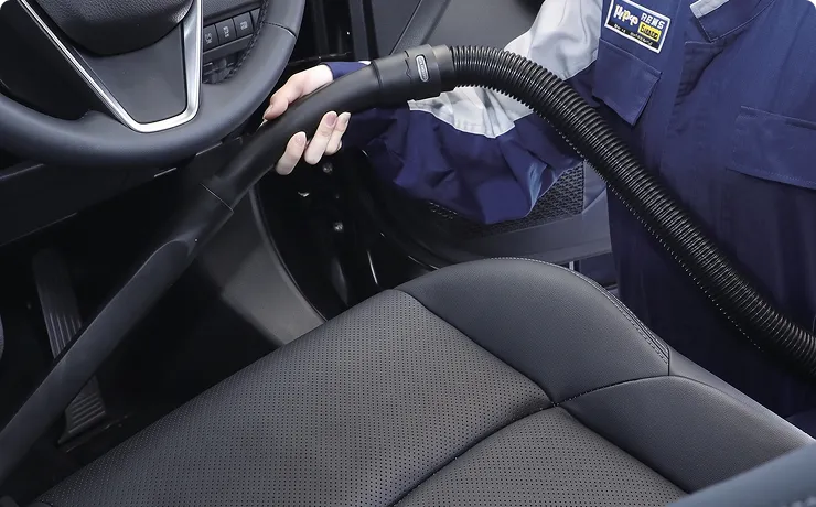 スタッフが掃除機で車内のシートまわりを清掃する様子